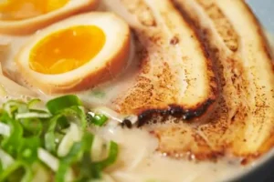 close-up of tonkotsu ramen with pork eggs and chives